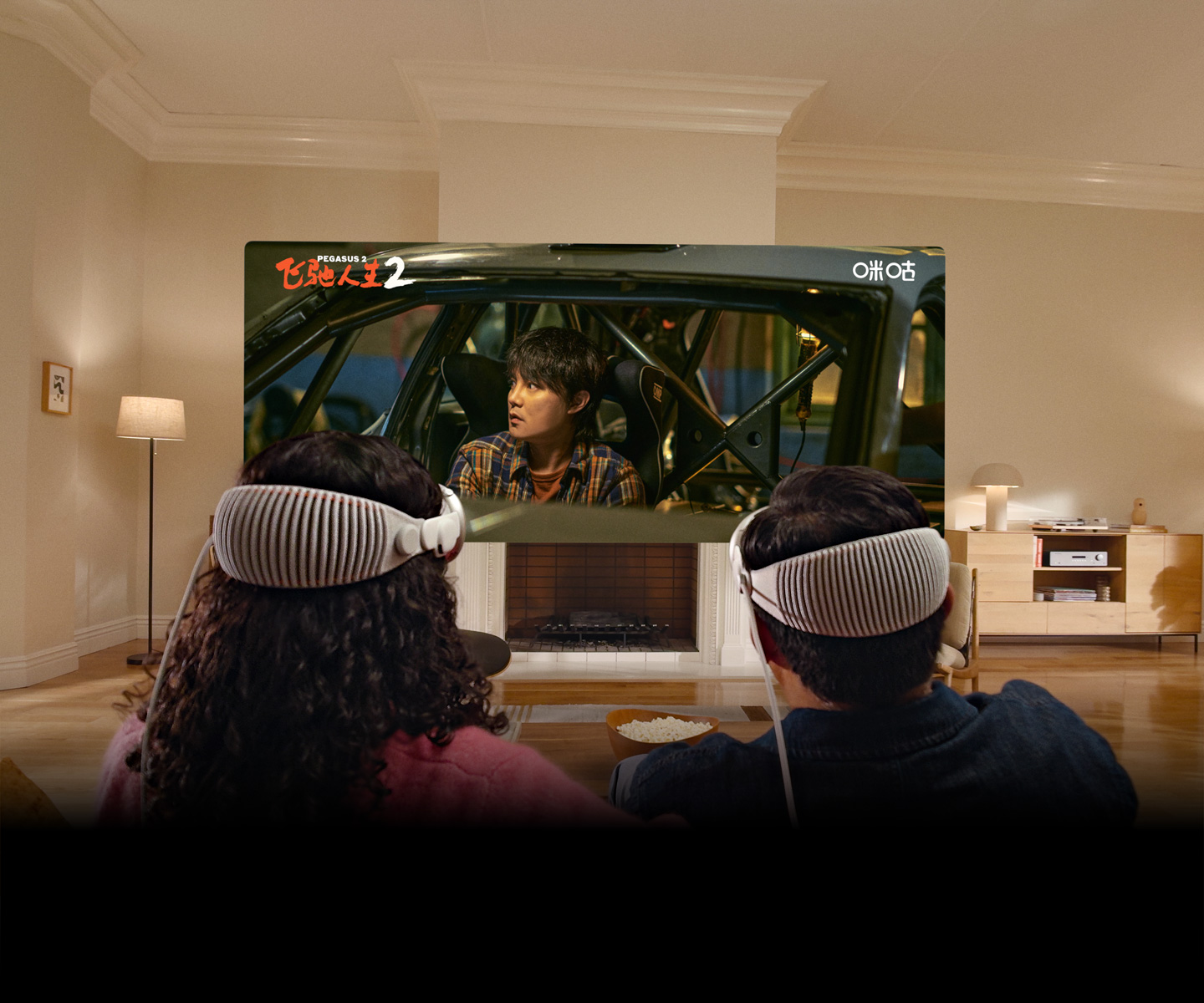 两个人头戴 Apple Vision Pro，并排坐在沙发上观看电影《飞驰人生 2》。