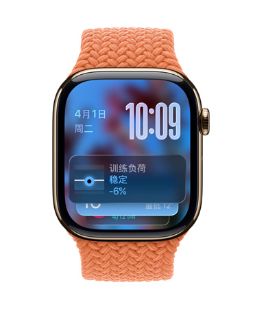 金色钛金属 Apple Watch 搭配橘红色编织表带，表盘左上角显示日期，右上角有数字显示时间，下方为训练负荷小组件，全部采用半透明 Liquid Glass 设计。