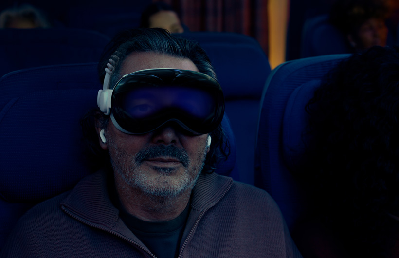一个人坐在飞机上，戴着装有双圈编织头带的 Apple Vision Pro。