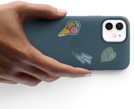 一只手拿着一部贴有贴纸的 iPhone 12。