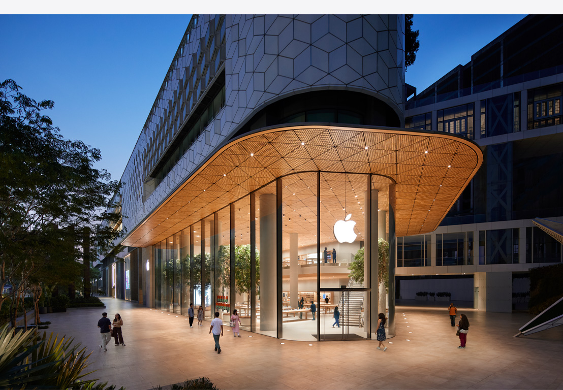 夜幕下的 Apple Store 零售店，玻璃窗内透出灯光，Apple 标志居中位于正门上方。