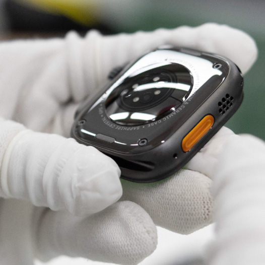 戴着手套的双手拿着背面朝上的 Apple Watch