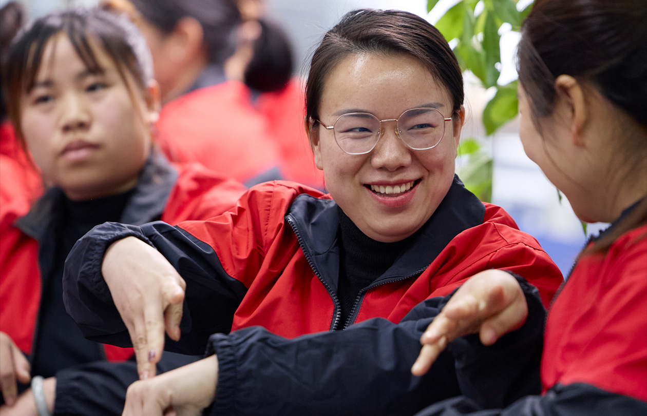 三名员工坐在一起，其中一个人正在对另一个人打手语