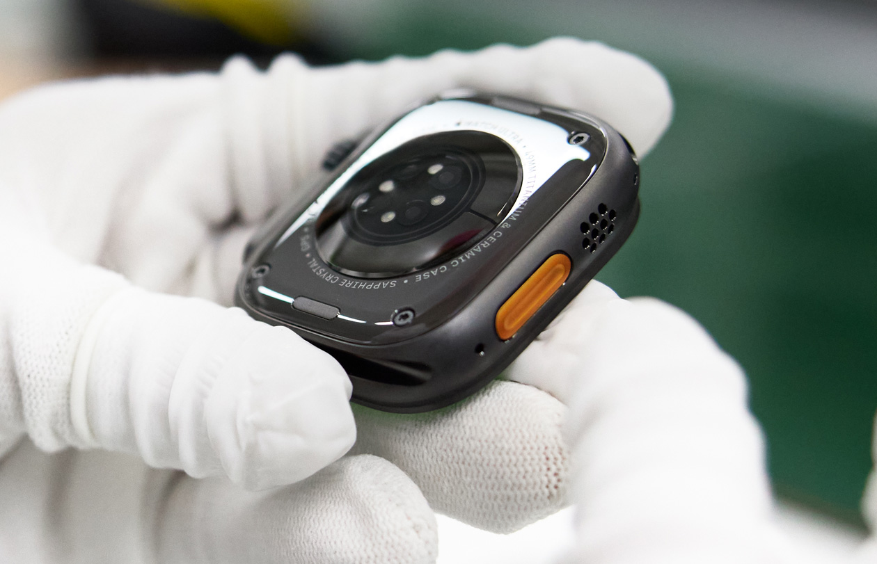 戴着手套的双手拿着背面朝上的 Apple Watch