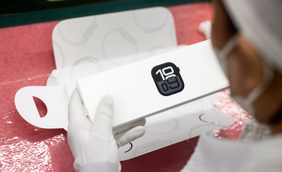 一名戴着口罩的员工包装 Apple Watch 的俯视图